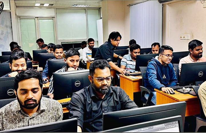 Students at Dell monitors working on lab exercises while the trainer checks a screen