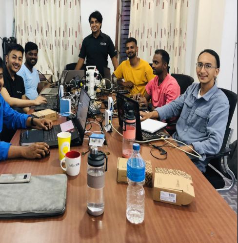 Trainer standing behind a table of smiling network engineers with laptops and routers